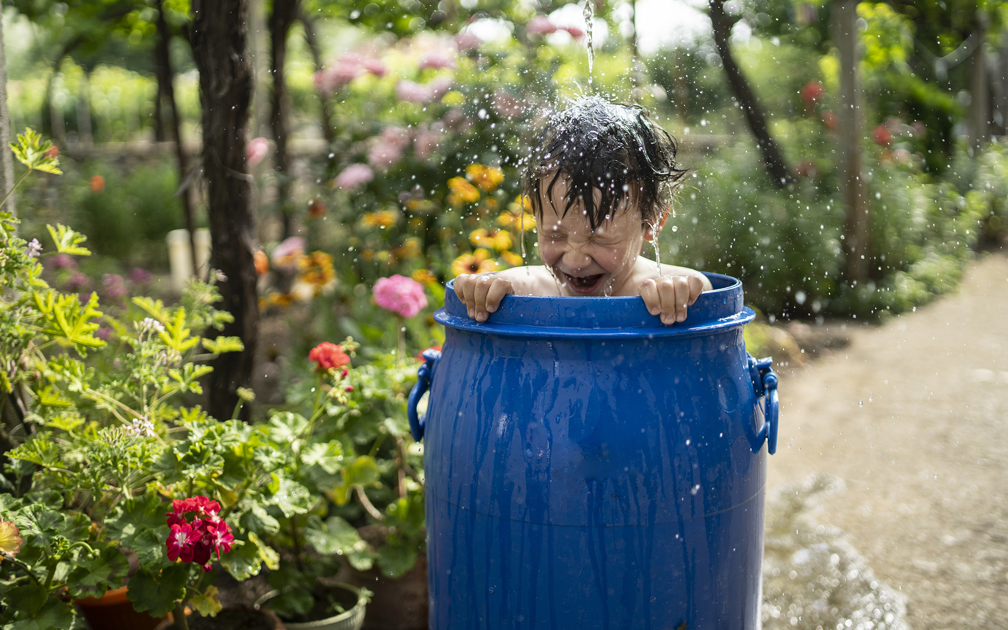Boy having fun playing with water in the garden.