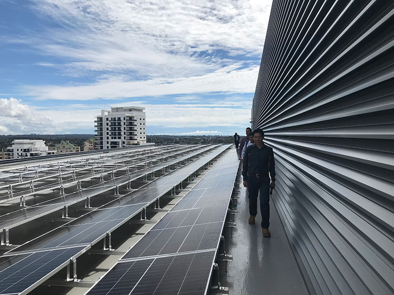 Image of people walking along a row of solar panels on the roof of a sustainable building