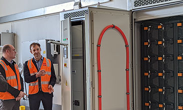 Staff standing by an open energy cabinet.