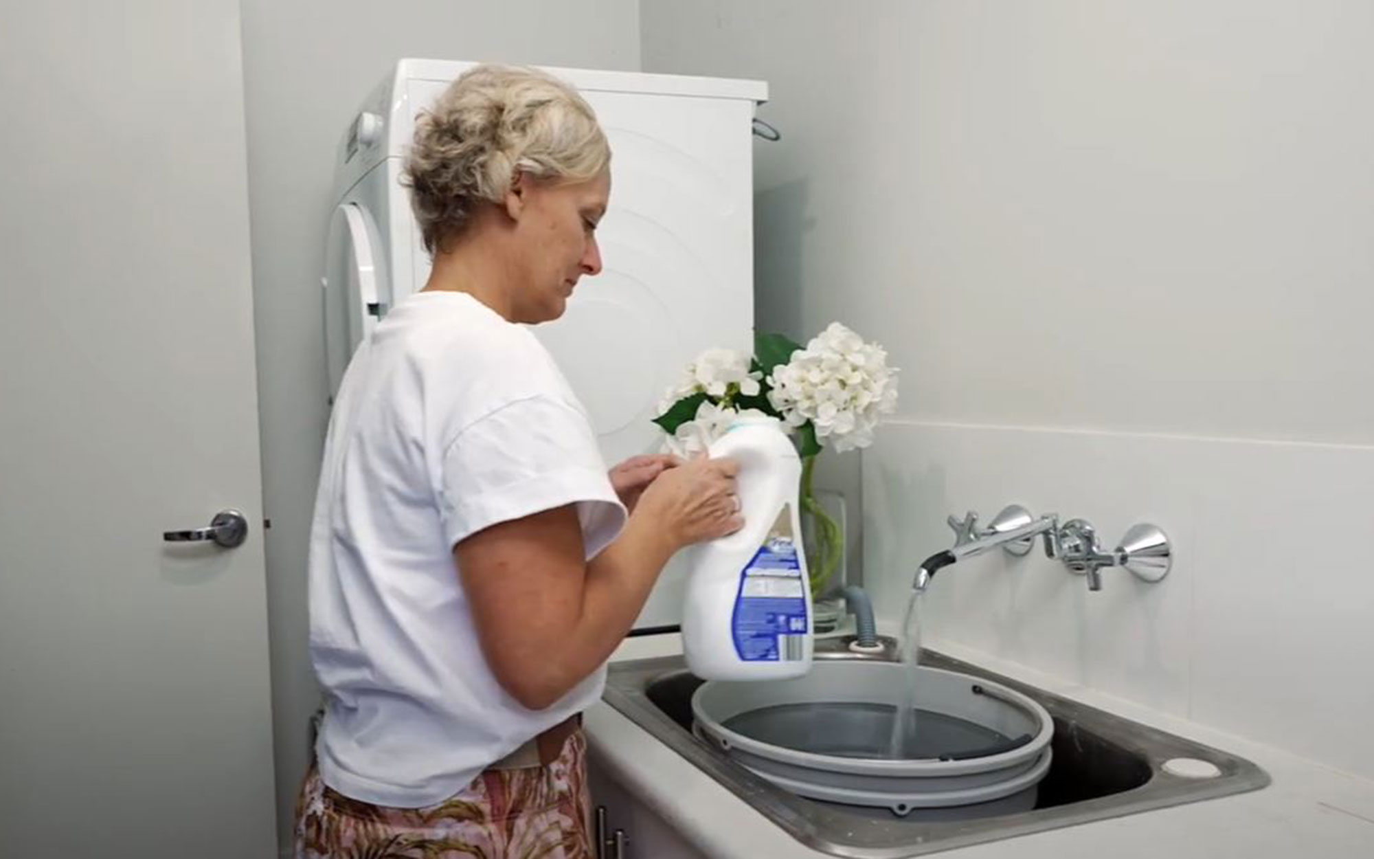 Woman putting washing liquid into washing machine