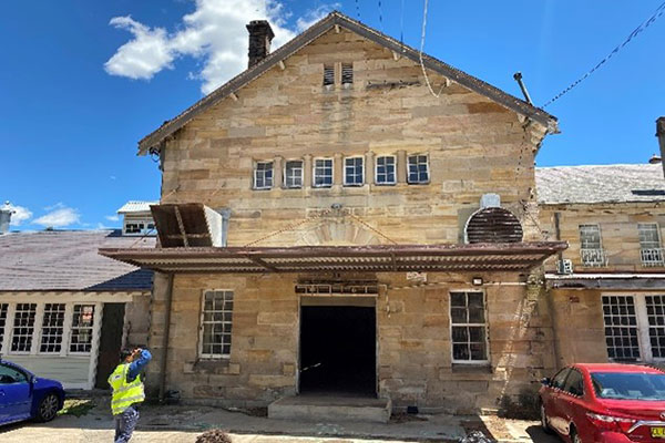 Heritage sandstone building in need of refurbishment with construction workers in foreground